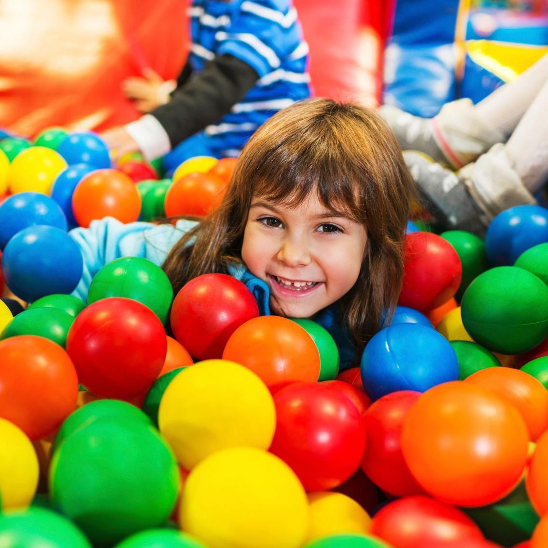 Niña sonriendo en piscina de pelotas de colores