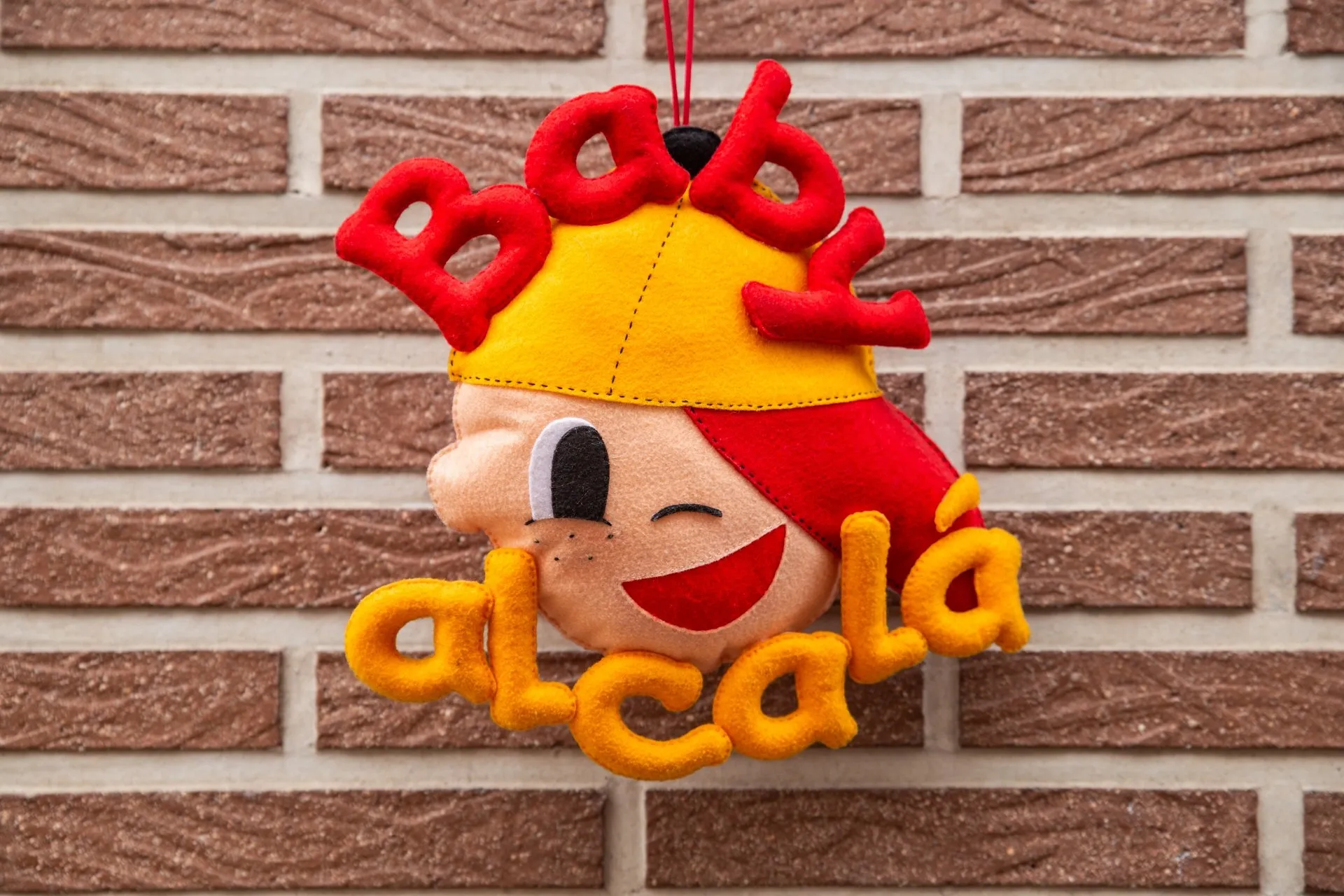 Peluche de niño sonriente con el nombre "Baby Alcalá"