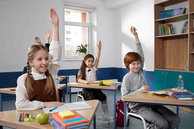 Niños levantando la mano en un aula